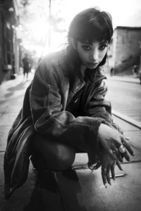 a woman squatting down on a sidewalk