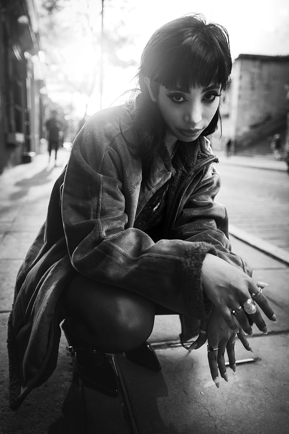 a woman squatting down on a sidewalk