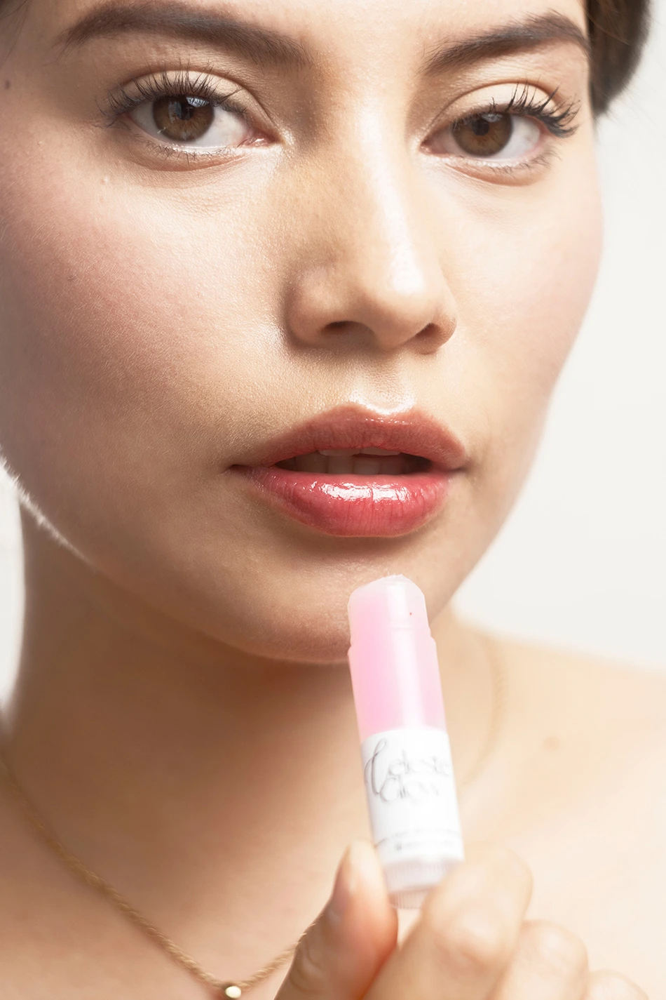 rostro de mujer morena sosteniendo un labial
