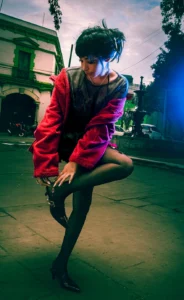 mujer joven usando abrigo rojo atandose las zapatillas frente a un parque