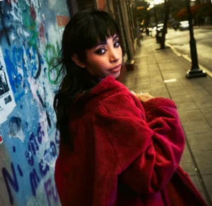 mujer joven con abrigo rojo camina por la calle de Oaxaca